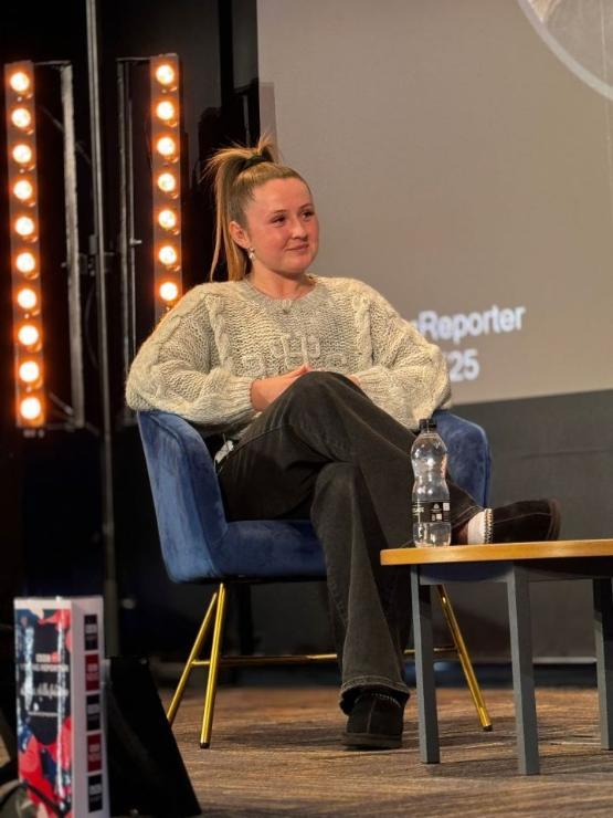 a person sat down on a stage listening to a question they are being asked