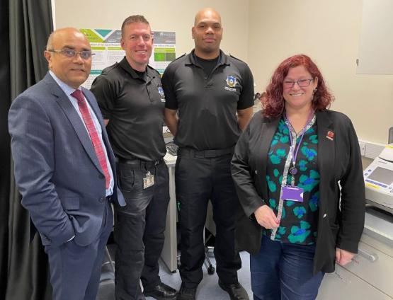 Two university staff members stood next to two firefighters in a university lab