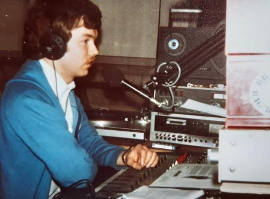 a student wearing a jacket in a radio studio pictured in the early 1980s