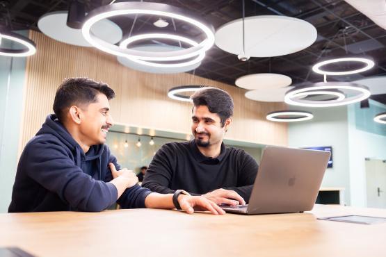 Two students chatting while using a laptop in Student Central