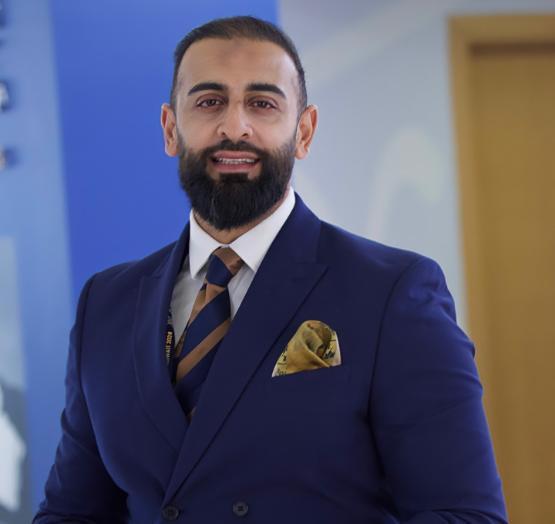 University staff member dressed in suit and tie looks towards the camera for a photograph