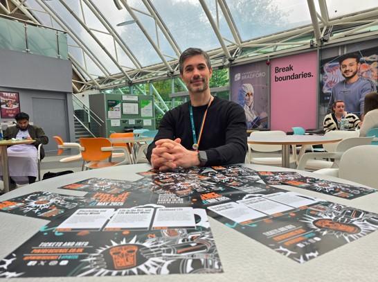 Dr Jacobo Elies seated at a table with Pint of Science flyers