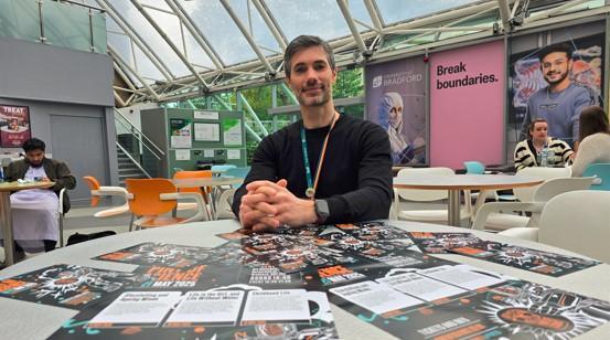 Dr Jacobo Elies seated at a table with Pint of Science flyers