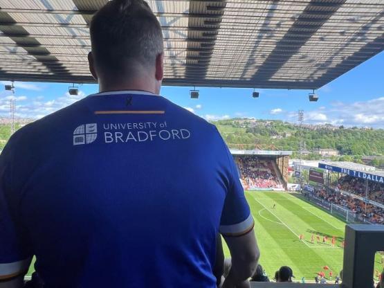A person with their back to the camera while watching a football match