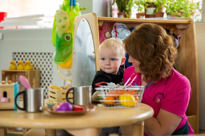 child and teacher in baby room