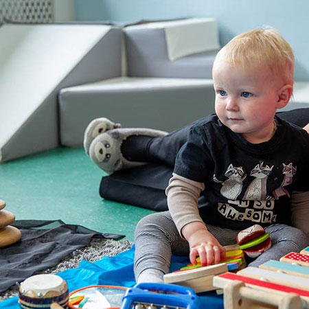 Baby sat at nursery with toys