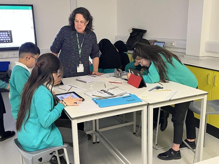 A teacher and students engaged in an activity around a desk