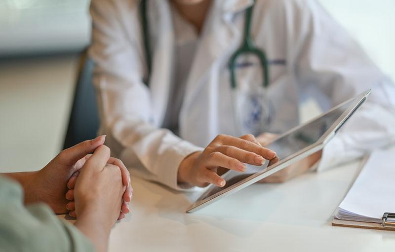 A doctor showing information to a patient on a digital device