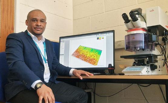 Dr Kavian Cooke at a monitor showing a scan of material surface