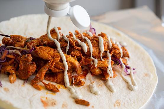 A chicken wrap with garlic mayo being made at Curb Chicken