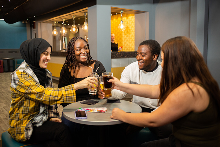 Four students with drinks in the Escape Lounge