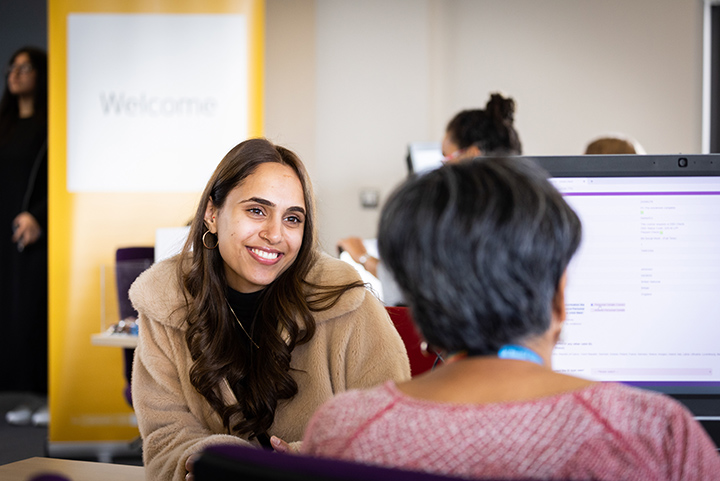 Smiling student speaking to a member of support staff