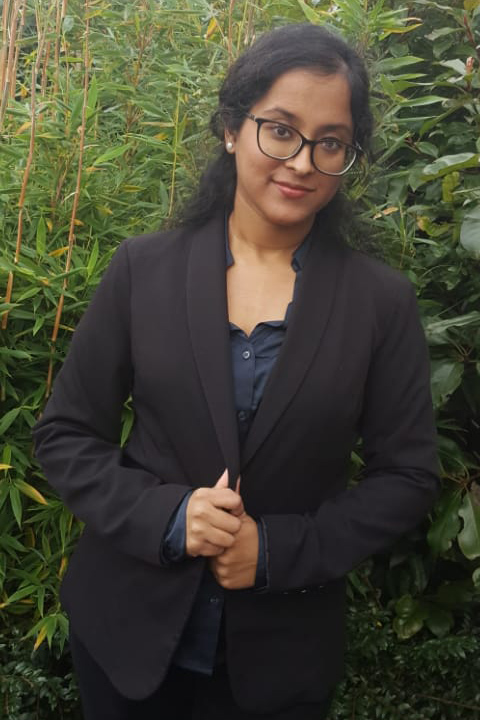 Sapna stood in front of some greenery.