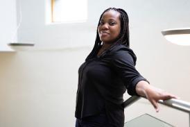 A person leaning back on a banister, smiling at the camera.