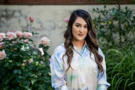 A person standing in front of some rose plants and a wall.