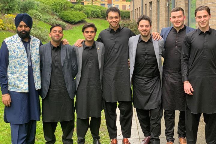 A group of smartly dressed students standing in a line outside the University of Bradford on-campus accommodation.