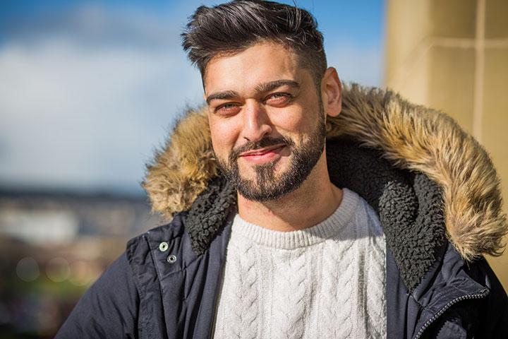 Close up of MPAS graduate Mobashar Rashid standing in front of the entrance to Richmond Building