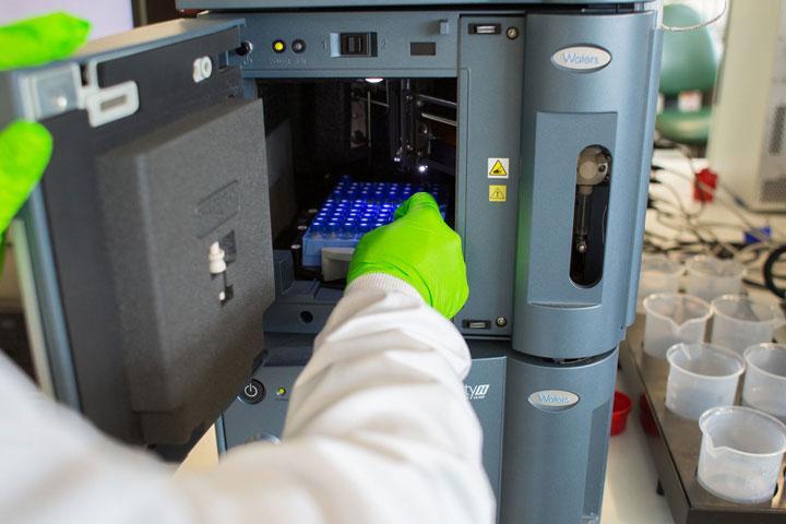 A gloved hand working with specimens in a pharmaceutical lab