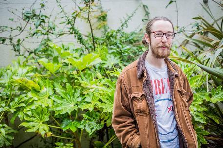 MA Filmmaking student Sam Kane standing in front of some plants