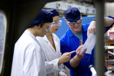 Two engineering students working with a University technician in an engineering lab