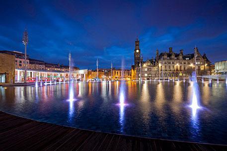 A large pool of water with lights and reflections from buildings at night