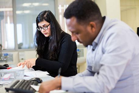 Two pharmacy students sitting at a desk writing notes.