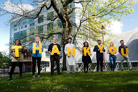 A group of students standing in a line holding up the letters to spell thank you.