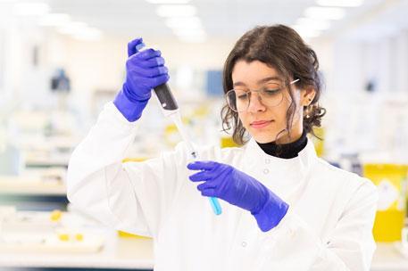 A student working in a lab with a syringe and test tube.