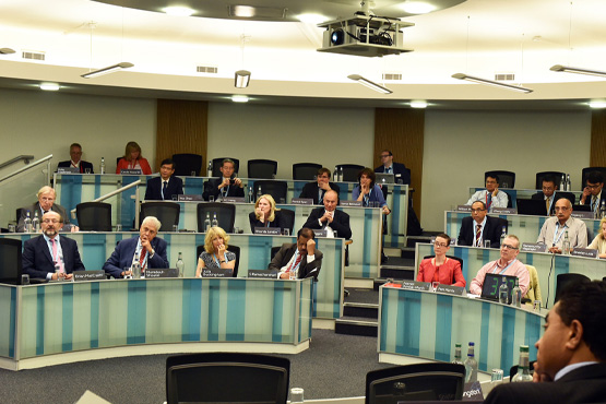 A person leading a conference to lots of attendees who are seated.