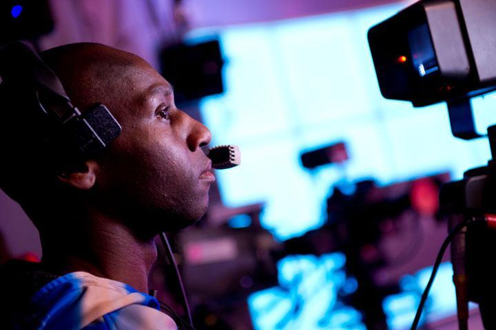 A male student filming in a television studio