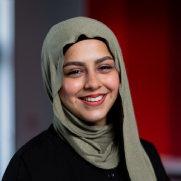 A student with a beige headscarf smiles at the camera.