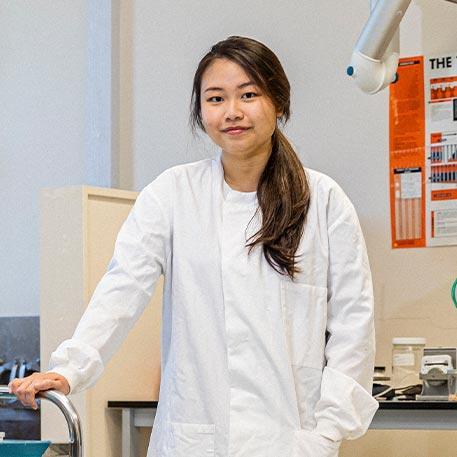 A student smiling at the camera in a lab.