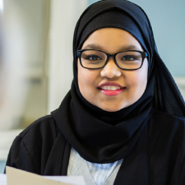 A student with a black headscarf smiles towards the camera.