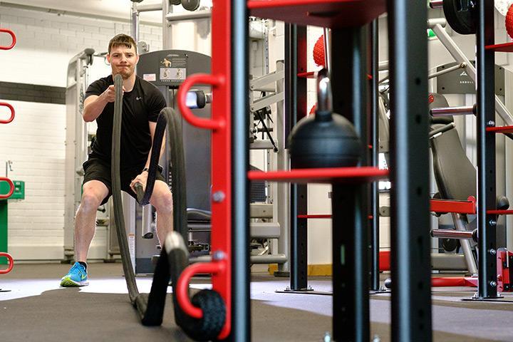 A male student using the battle ropes in the Unique gym