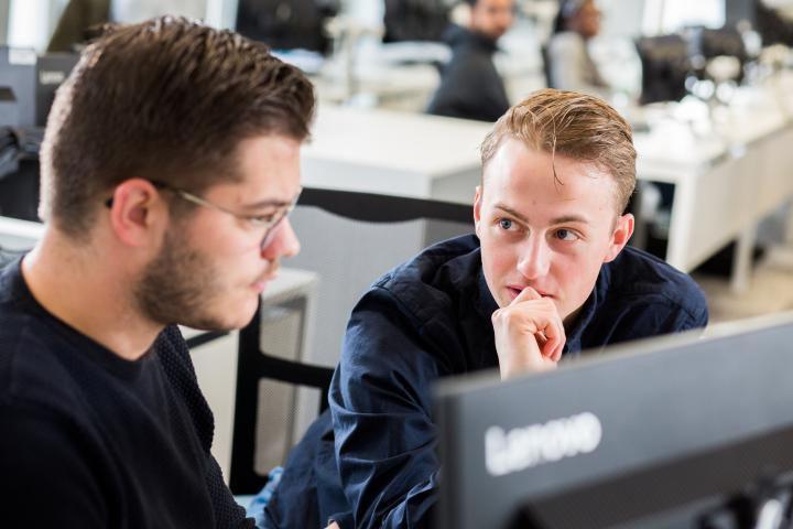 Two business students sat behind a computer.