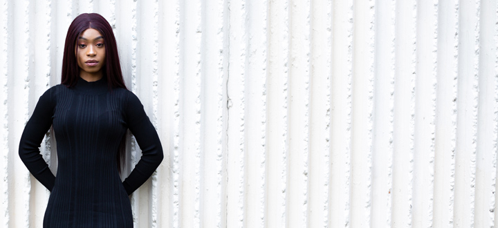 Public Health student, Vanessa Naddamba stood in front of a white textured wall.