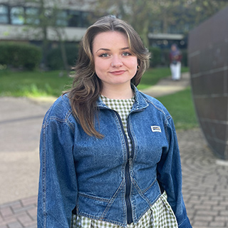 A student on the University campus, smiling at the camera